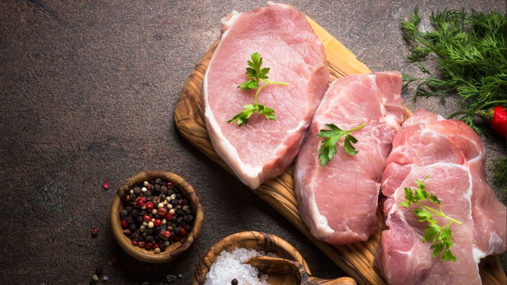 Pork on a cutting board with herbs