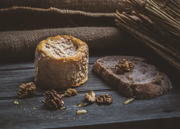 Baked cheese wheel served with rustic bread and walnuts