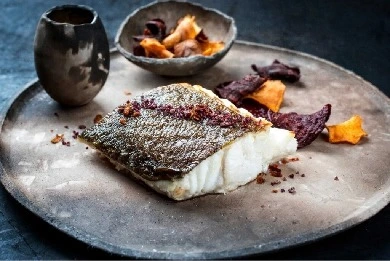 Pan-seared fish fillet plated with colorful vegetables on ceramic plate