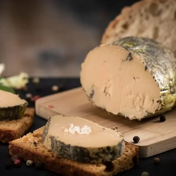 Sliced duck foie gras terrine on wooden cutting board