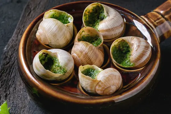 Baked escargot snails with garlic and herb butter in a traditional dish